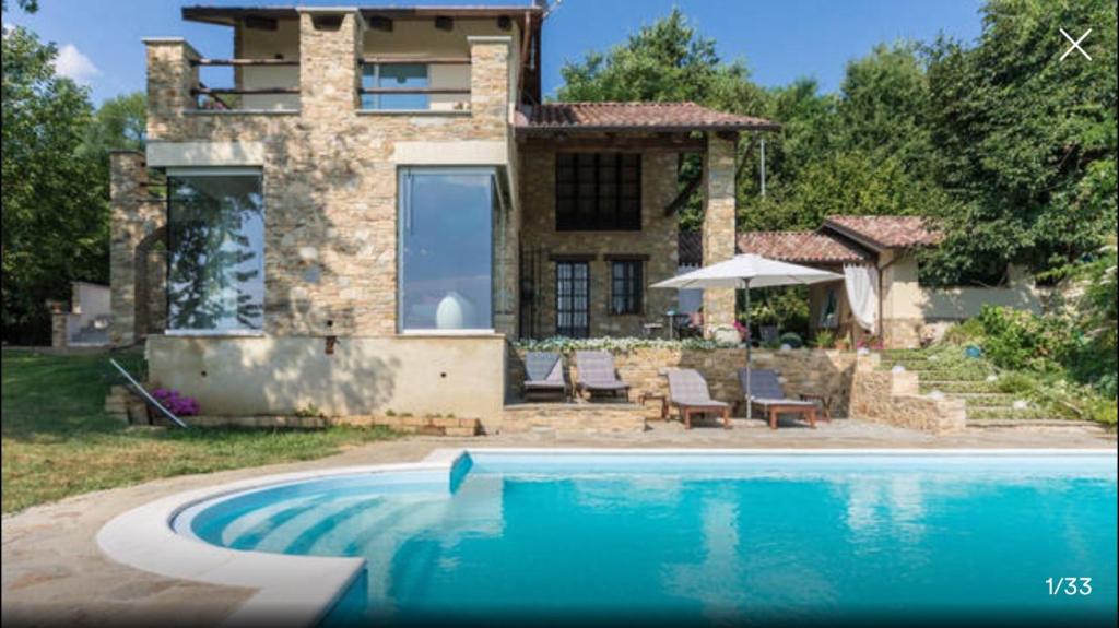a stone house with a swimming pool in front of it at Piscina e relax nelle Langhe Villa Gaia in Bra