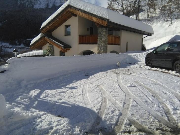een met sneeuw bedekte oprit van een huis met een auto erin bij Appartamento Sole in Morgex