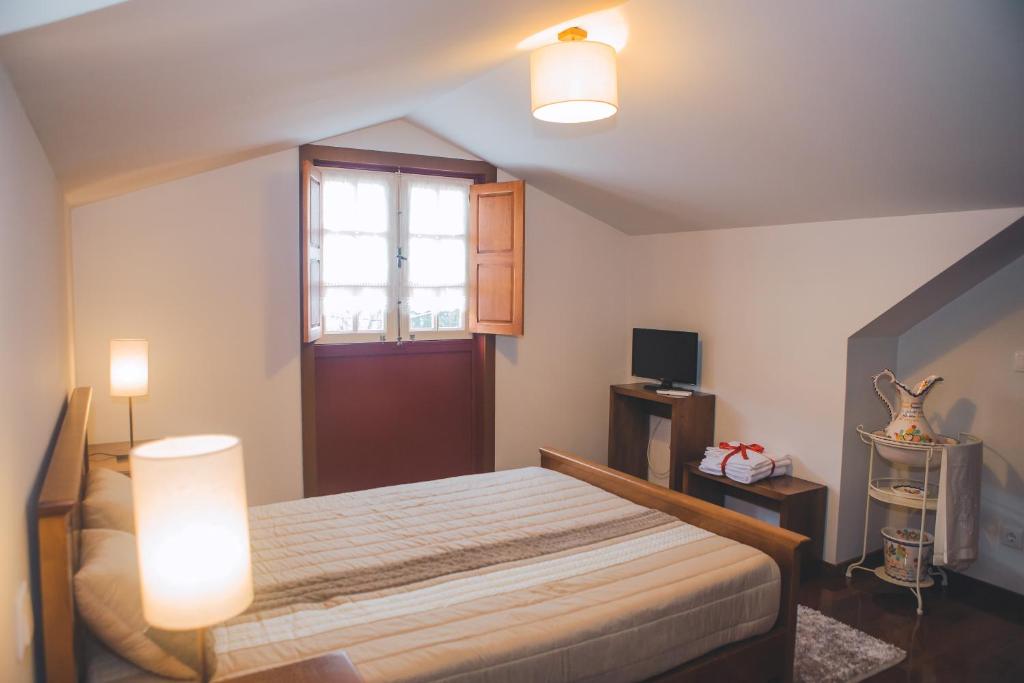 een slaapkamer met een bed met 2 verlichting en een raam bij Casa da Obrinha in Bouro