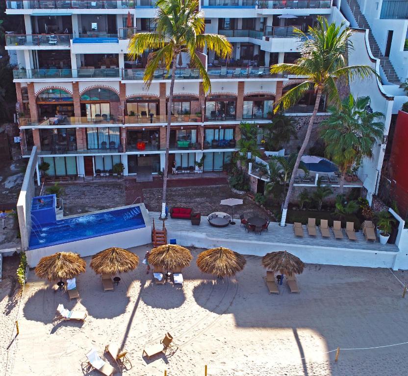 Vallarta Shores Beach Hotel في بويرتو فايارتا: مجموعة من مظلات القش أمام المبنى