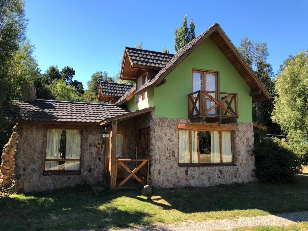 a green house with a wooden door and windows at Complejo Duendes del Maiten in San Carlos de Bariloche