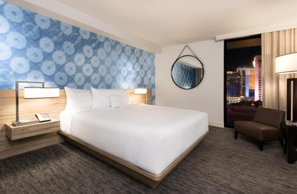 a bedroom with a large white bed and a chair at The LINQ Hotel and Casino in Las Vegas