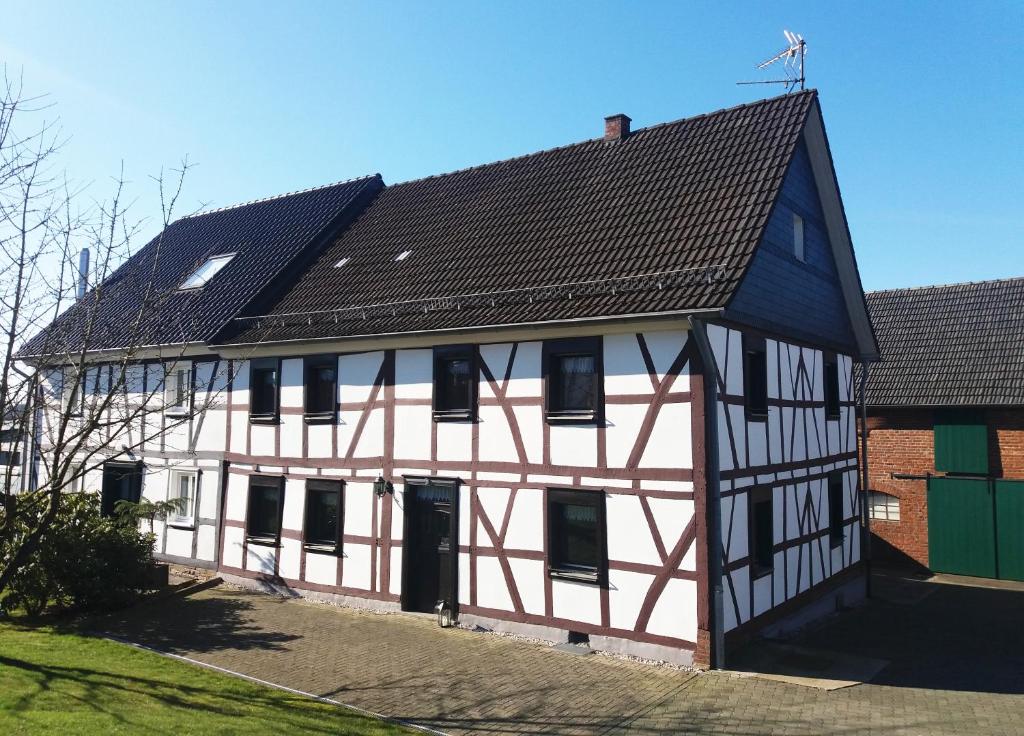 a white and red building with a black roof at Gräfrath Gästehaus Neunkirchen-Seelscheid in Söntgerath