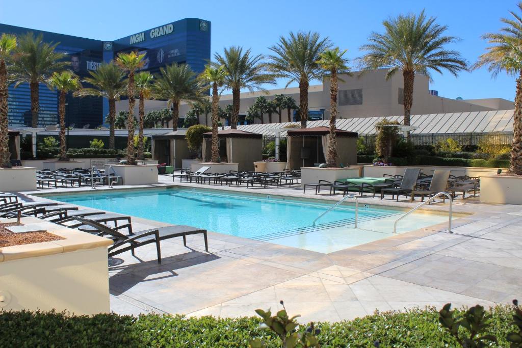 a swimming pool with chaise lounge chairs and palm trees at Luxury Suites International at The Signature in Las Vegas