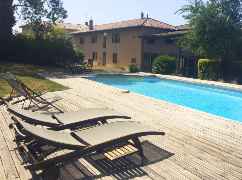 a swimming pool with two lounge chairs next to a house at La Grange de la Batone - Bed and Breakfast in Messimy