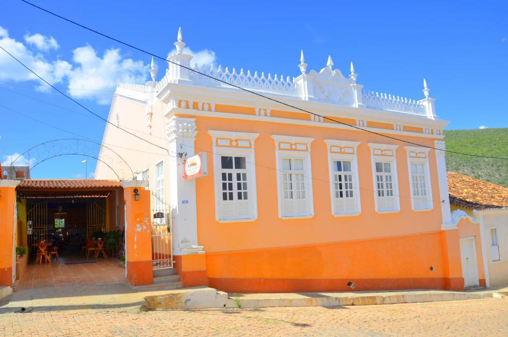 an orange building with white windows on a street at Hotel e Pousada O Casarão in Palmeiras