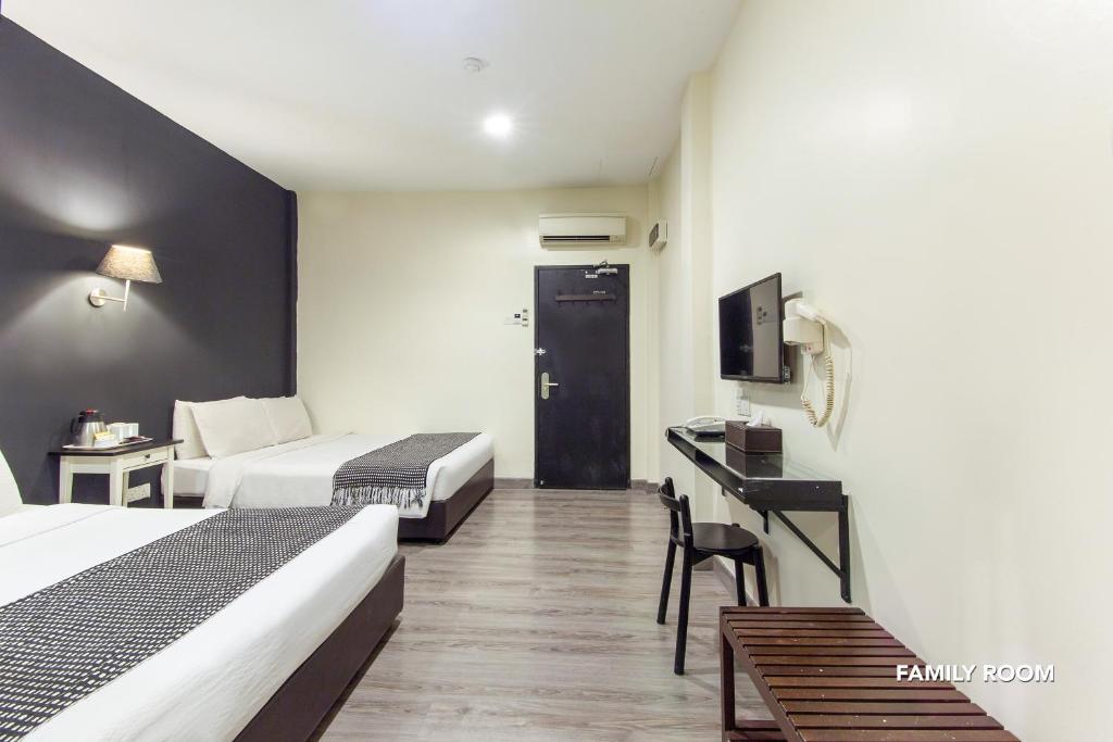 A family room with two beds, a narrow desk and a wall-mounted television.