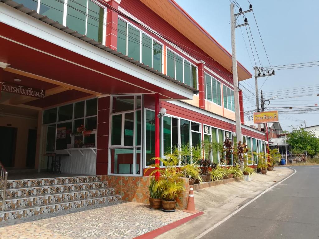 a red building with potted plants outside of it at Khong Chiam 2 Hotel in Khong Chiam