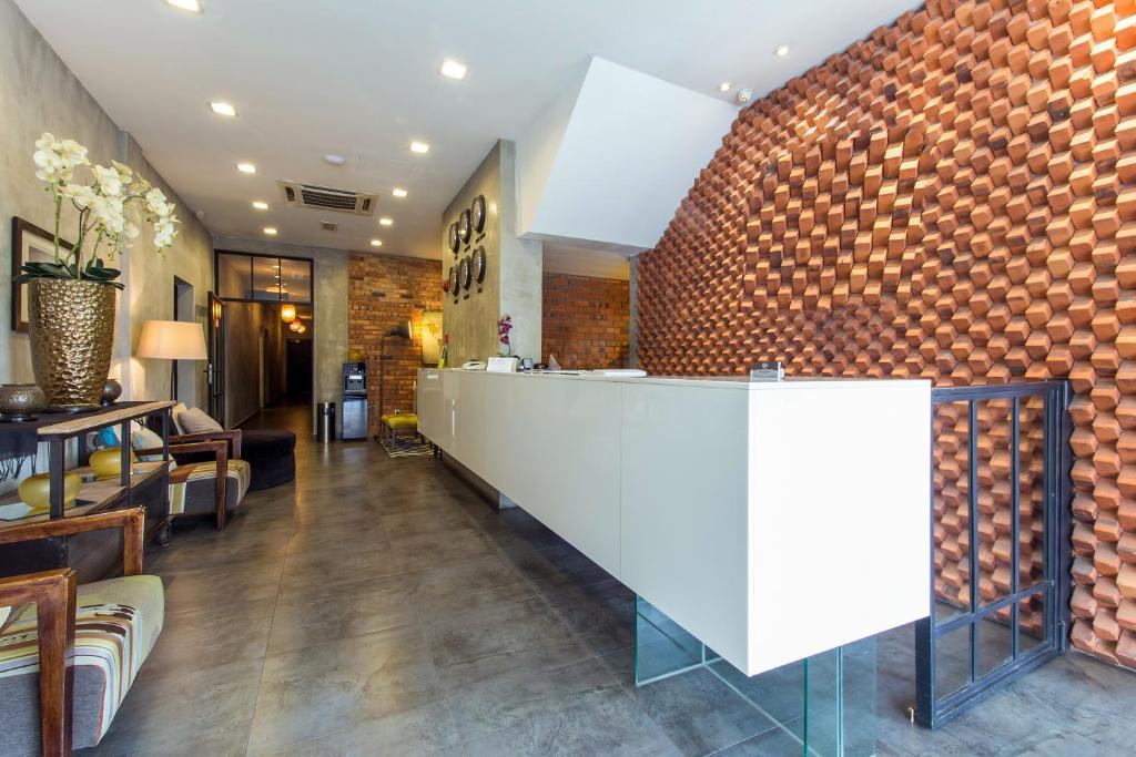A hotel dining or reception area with a white counter and a striking textured brick feature wall.