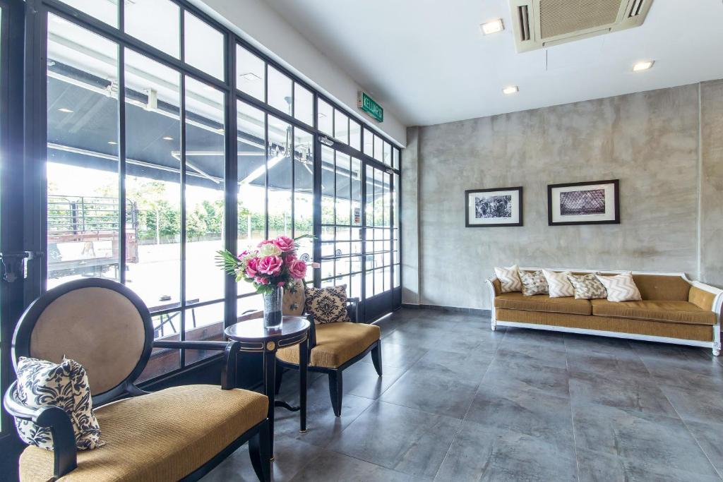 A bright lobby seating area with a sofa, armchairs and glass doors opening toward an outdoor space.