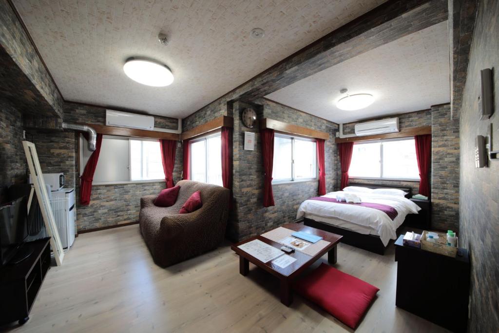 een slaapkamer met een bed, een bank en een tafel bij La Foret Fujimi in Hiroshima