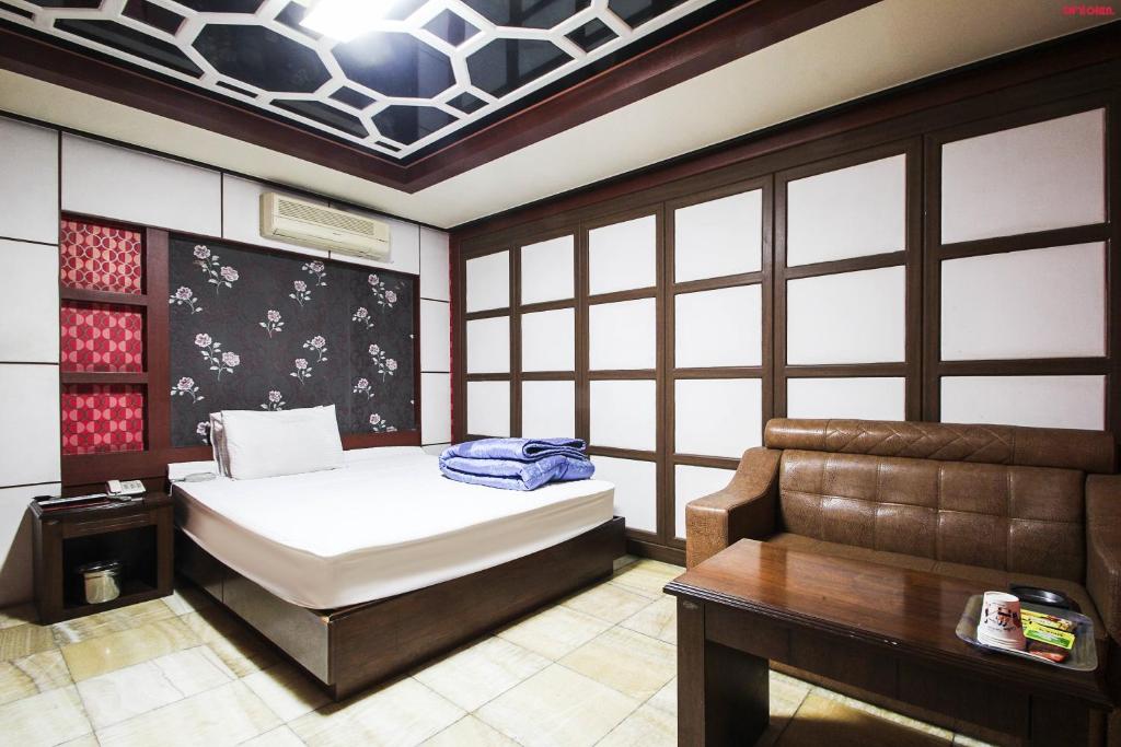 Plus Motel في بوسان: غرفة نوم بسرير وطاولة واريكة