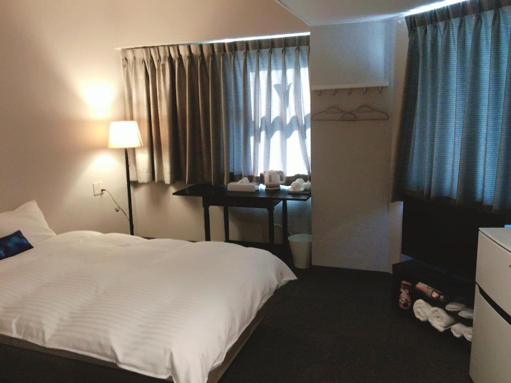 岡山市にあるホテルオクシオのベッド、デスク、窓が備わるホテルルームです。