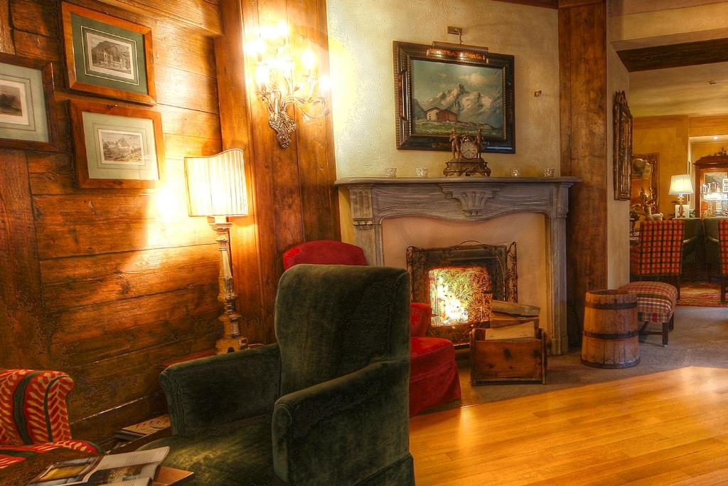 a living room with a fireplace and a green chair at Villa Novecento Romantic Hotel - Estella Hotel Collection & Experience in Courmayeur