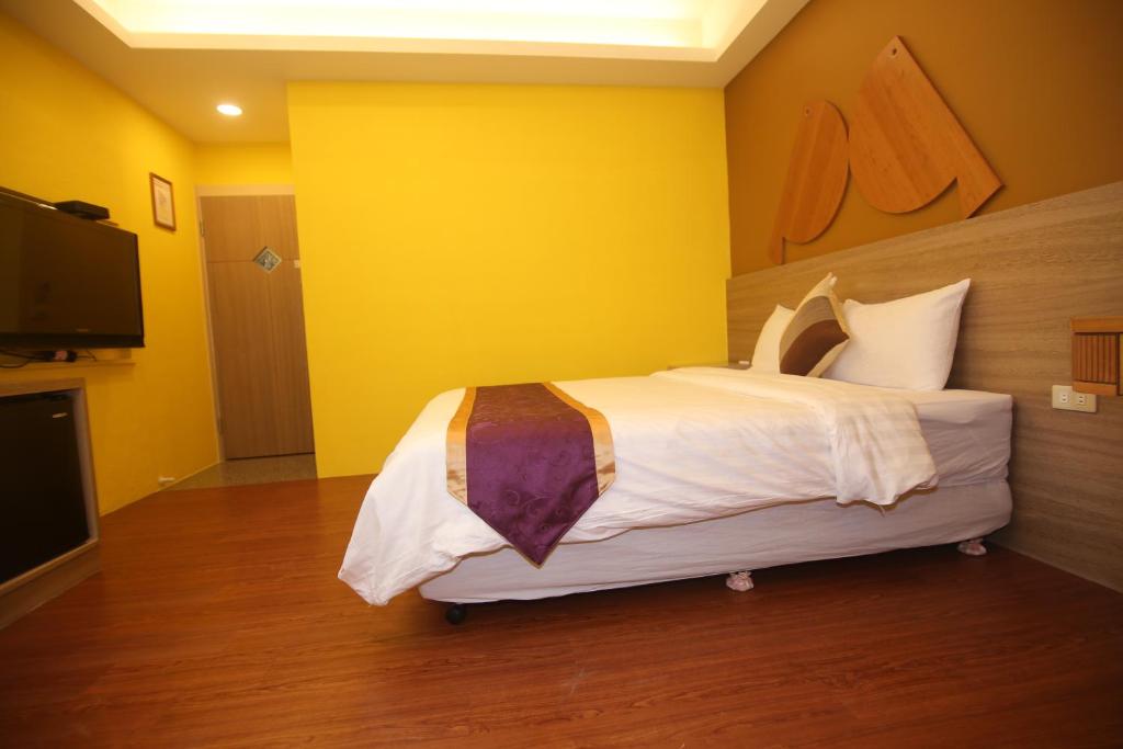 a bedroom with a large bed with a yellow wall at Kenting Waterfront Hotel in Kenting