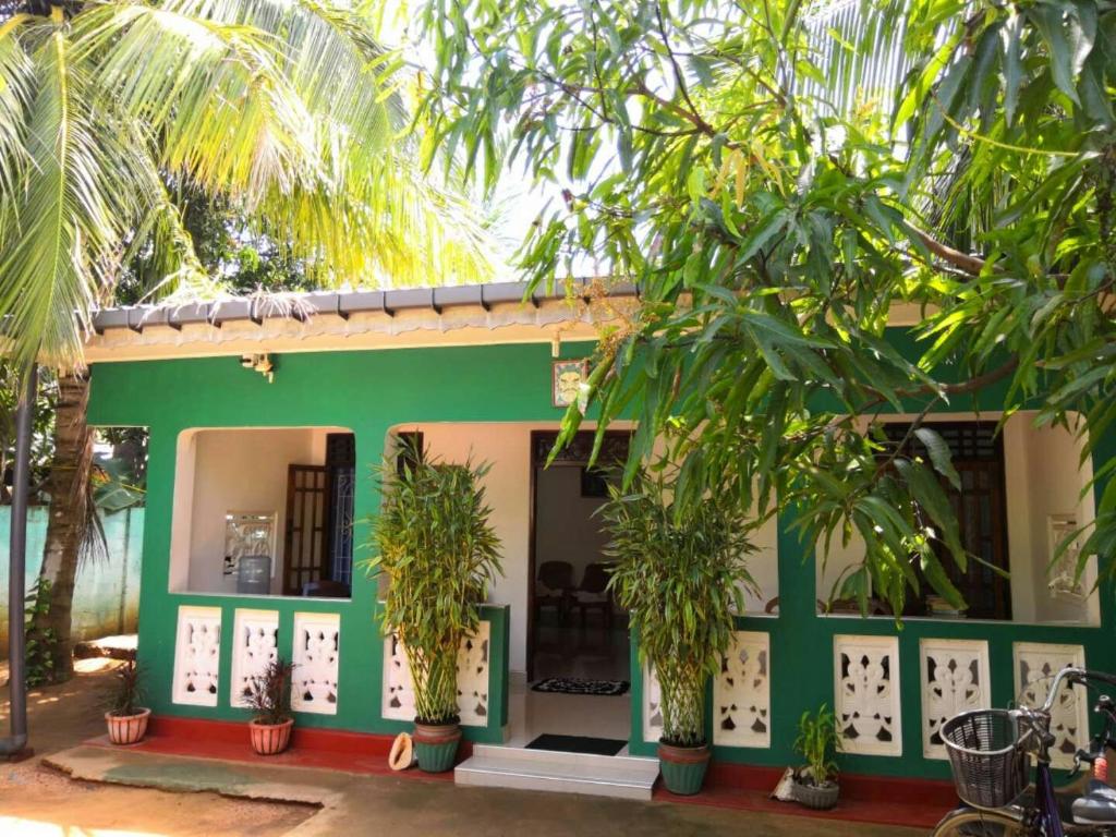 a green house with palm trees in front of it at Alass Ga for pets lovers in Trincomalee