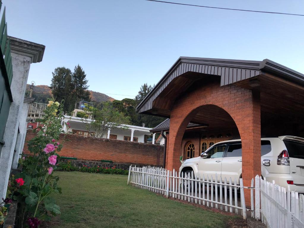 a white car parked in front of a brick building at Bungalow 28 in Nuwara Eliya
