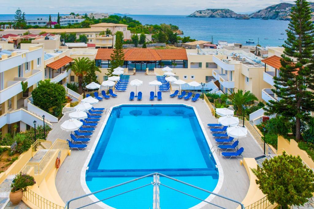 einen Blick über einen Pool mit Stühlen und Sonnenschirmen in der Unterkunft Alexander House Hotel in Agia Pelagia