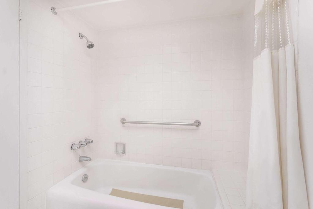 a white bathroom with a tub and a shower curtain at Howard Johnson by Wyndham Commerce GA in Commerce