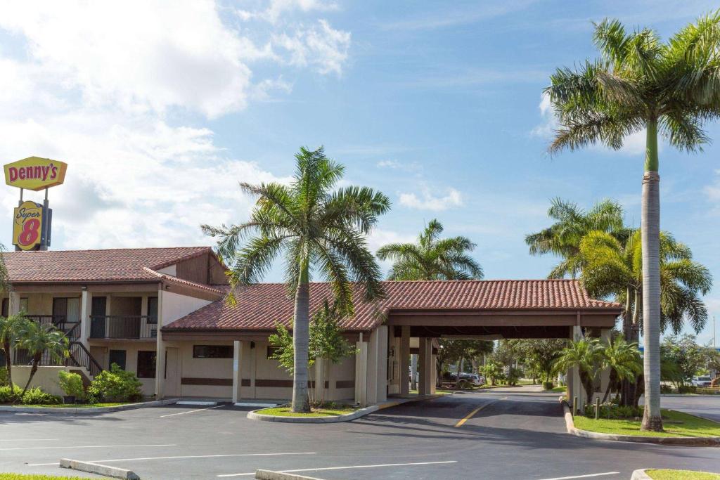 a hotel with palm trees in a parking lot at Super 8 by Wyndham Riviera Beach West Palm Beach in Riviera Beach