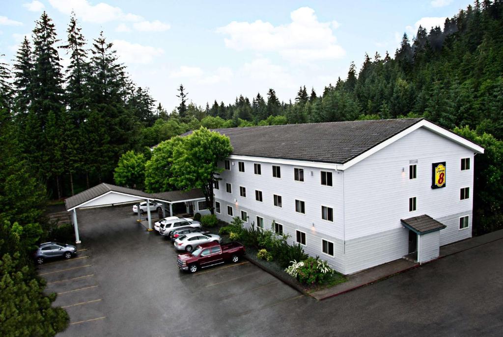 ein großes weißes Gebäude mit Autos auf einem Parkplatz in der Unterkunft Super 8 by Wyndham Juneau in Juneau