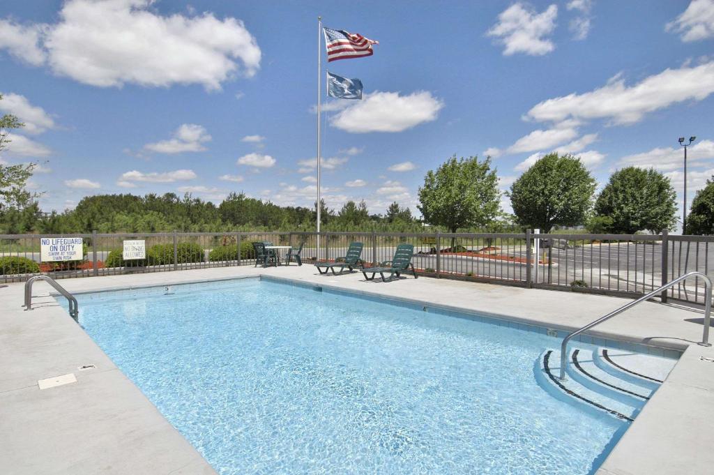 a swimming pool with an american flag and two chairs at Super 8 by Wyndham Richburg/Chester Area in Richburg