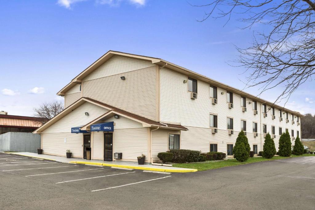 a large white building with a parking lot at Travelodge by Wyndham Battle Creek in Battle Creek