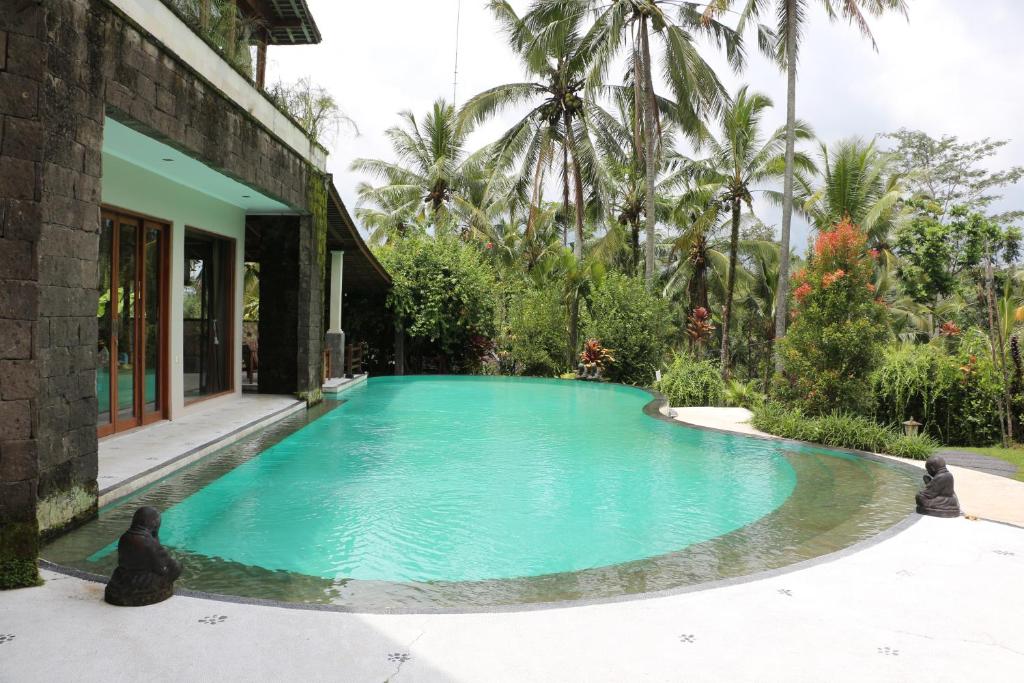 a swimming pool in front of a house at The Alise Villa in Tegalalang