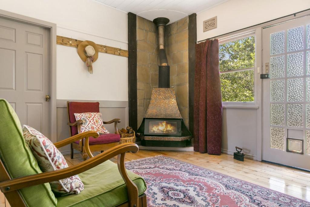 a living room with a fireplace and a green chair at Carinya Cottage in Katoomba