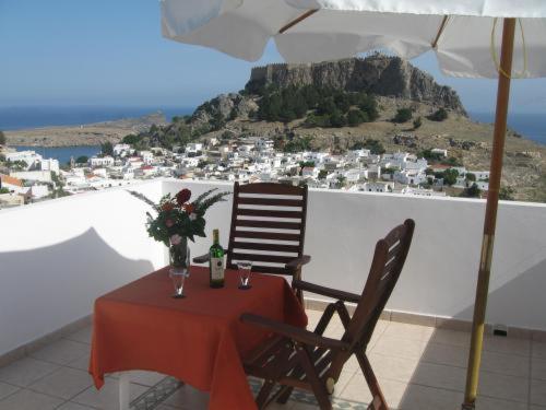 einen Tisch mit einer Flasche Wein, einem Stuhl und einem Regenschirm in der Unterkunft Chrysa Studios in Lindos