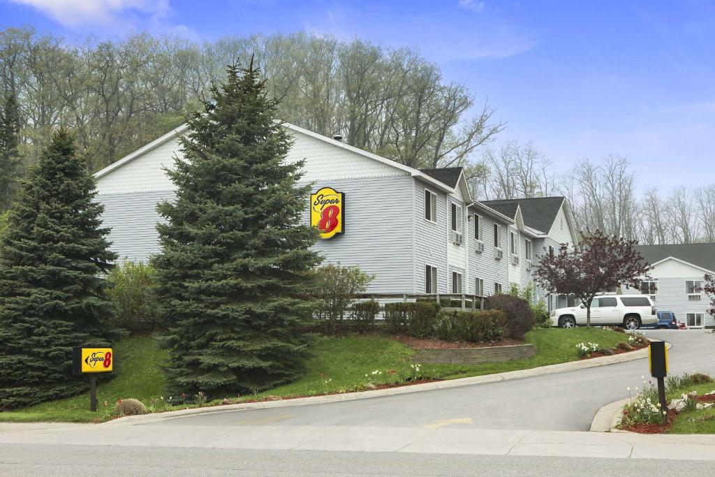 a white house with a sign on the side of a street at Super 8 by Wyndham Manistee in Manistee