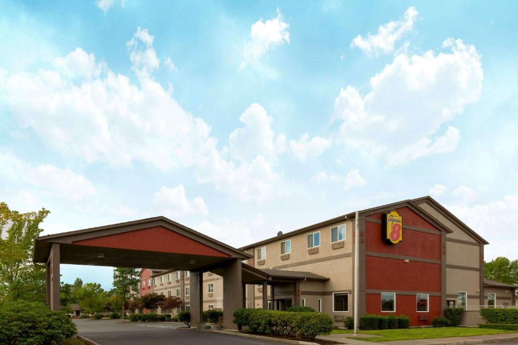 a hotel with a building and a sky with clouds at Super 8 by Wyndham Woodburn in Woodburn