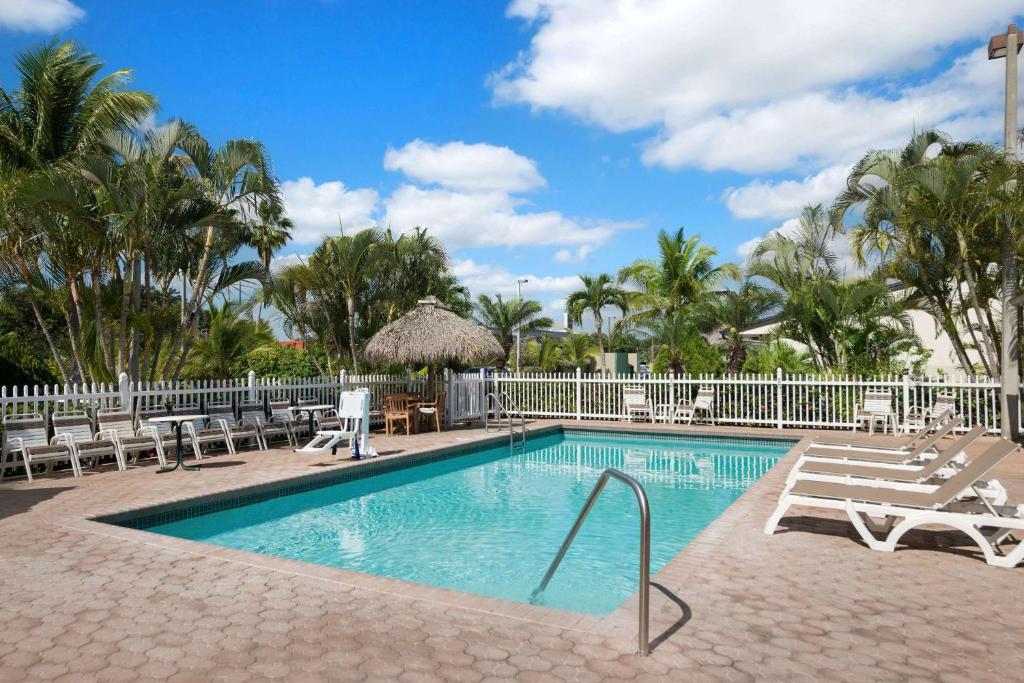 uma piscina com espreguiçadeiras e um resort em Travelodge by Wyndham Florida City/Homestead/Everglades em Florida City