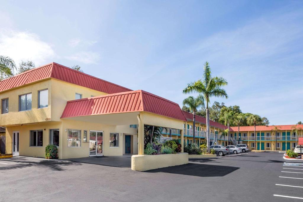 Super 8 by Wyndham Sarasota Near Siesta Key في ساراسوتا: فندق بسقف احمر وموقف سيارات