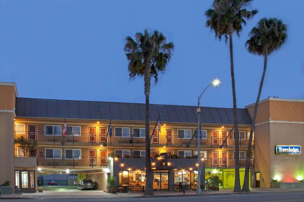 a hotel with palm trees in front of a building at Travelodge by Wyndham Culver City in Los Angeles
