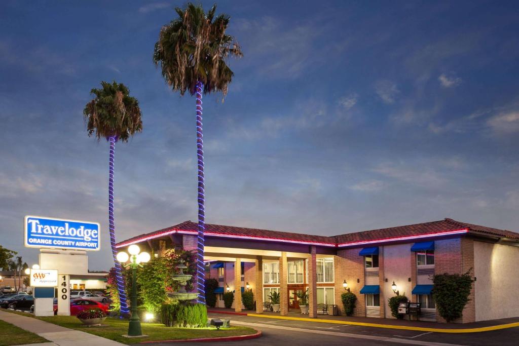a hotel with two palm trees in front of it at Travelodge by Wyndham Orange County Airport/ Costa Mesa in Costa Mesa