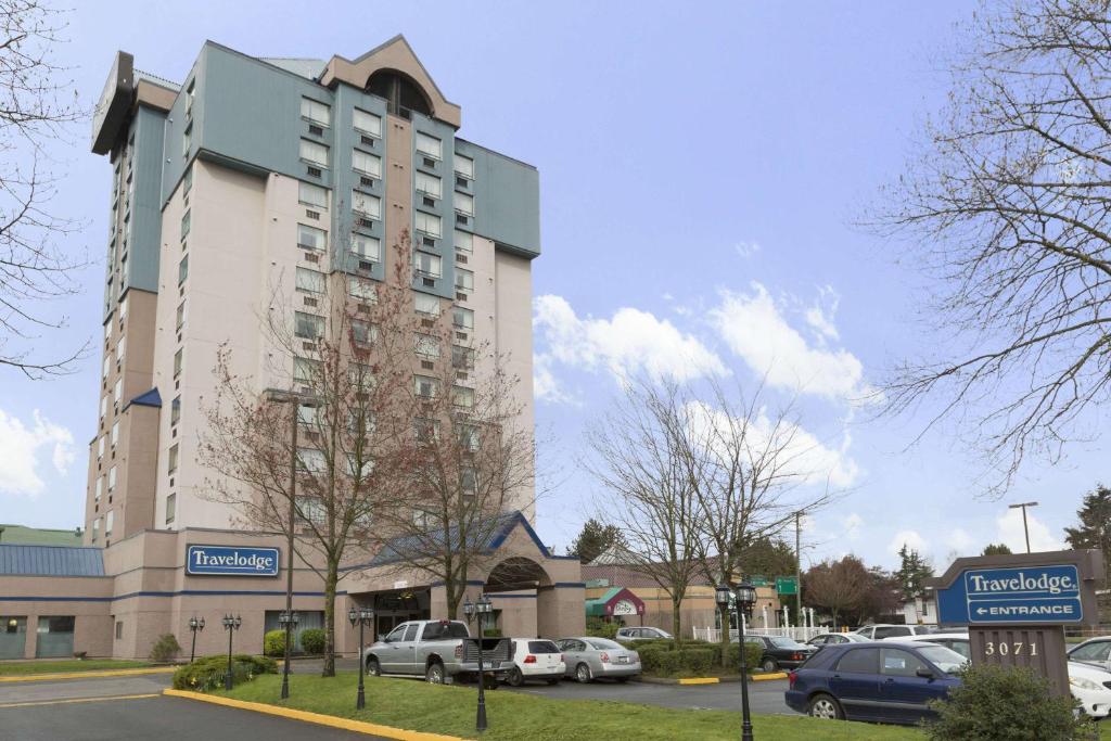 um grande edifício com carros estacionados num parque de estacionamento em Travelodge Hotel by Wyndham Vancouver Airport em Richmond