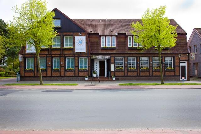 un gran edificio de madera con árboles delante de él en Hotel Meeresruh Garni, en Cuxhaven