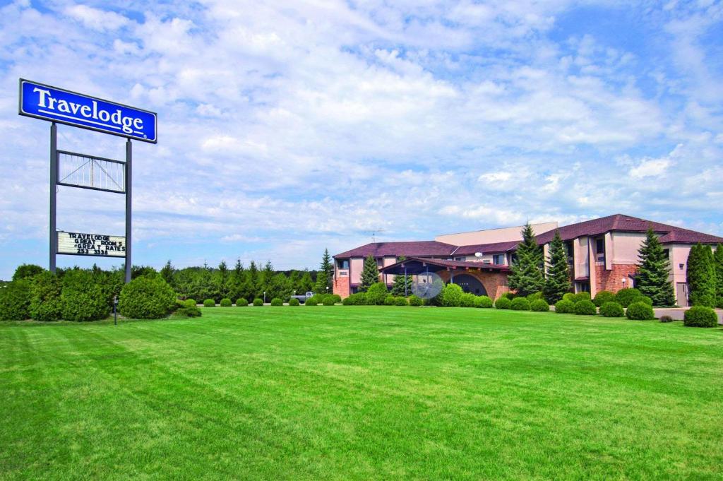 a sign in a field in front of a building at Travelodge by Wyndham Motel of St Cloud in Saint Cloud