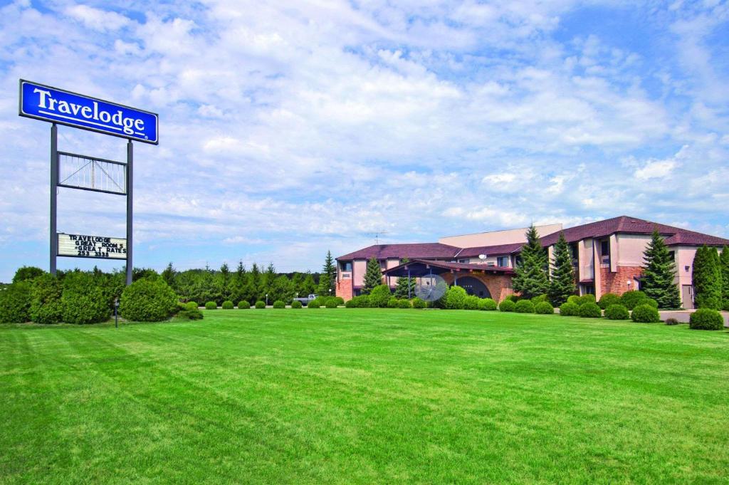 a sign in a field in front of a building at Travelodge by Wyndham Motel of St Cloud in Saint Cloud