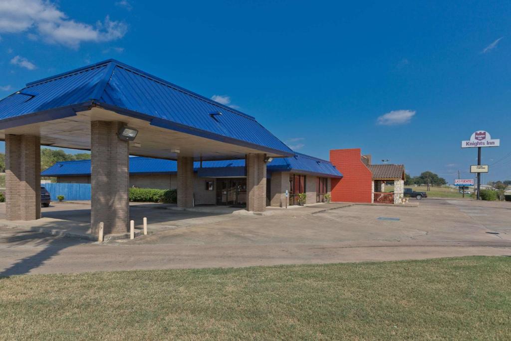 een tankstation met een blauw dak bij Knights Inn Brenham in Brenham