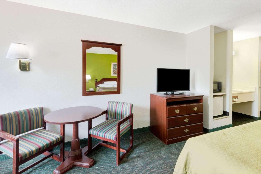 um quarto de hotel com uma mesa e cadeiras e uma televisão em Super 8 by Wyndham De Soto em De Soto