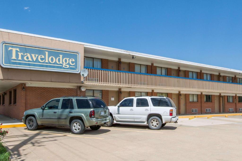 two vehicles parked in a parking lot in front of a motel at Travelodge by Wyndham Great Bend in Great Bend