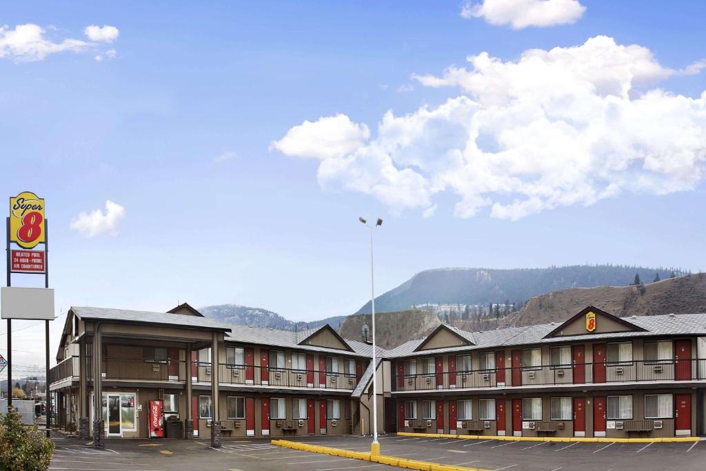 a hotel building with mountains in the background at Super 8 by Wyndham Kamloops East in Kamloops