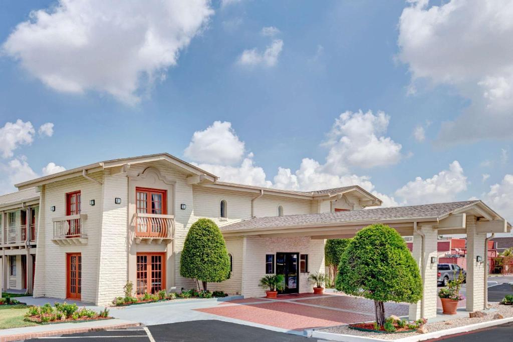 un gran edificio blanco con ventanas rojas en Travelodge by Wyndham North Richland Hills/Dallas/Ft Worth, en North Richland Hills