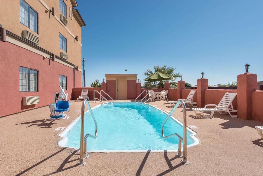 a swimming pool with chairs and a table at Super 8 by Wyndham Abilene South in Abilene