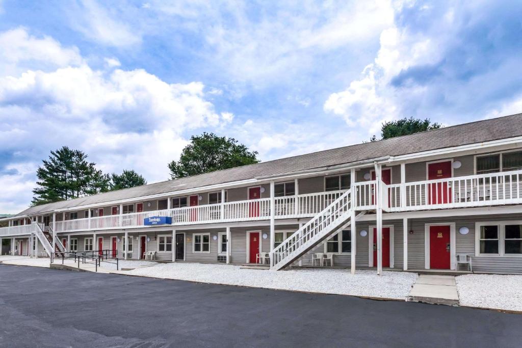 a large white building with red doors and a parking lot at Travelodge by Wyndham Great Barrington Berkshires in Great Barrington