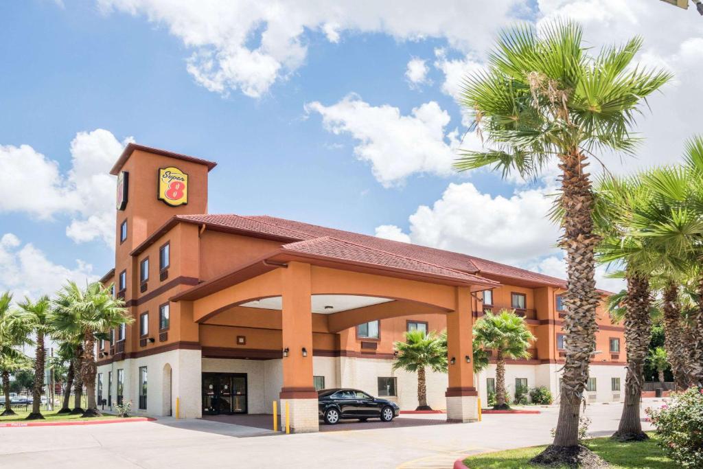 a hotel with palm trees in front of it at Super 8 by Wyndham Brookshire TX in Brookshire