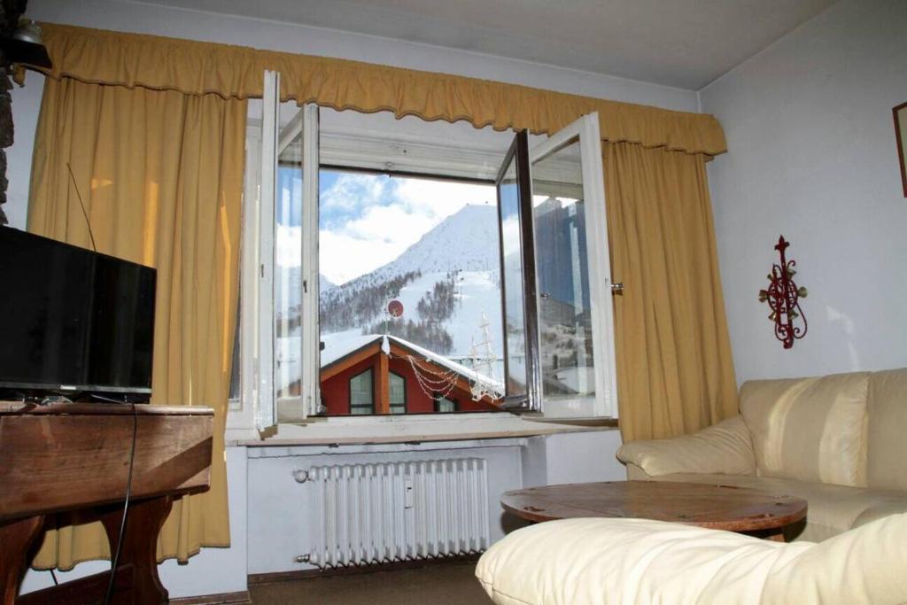 a living room with a couch and a large window at Alloggio a Sestriere fronte piste in Sestriere