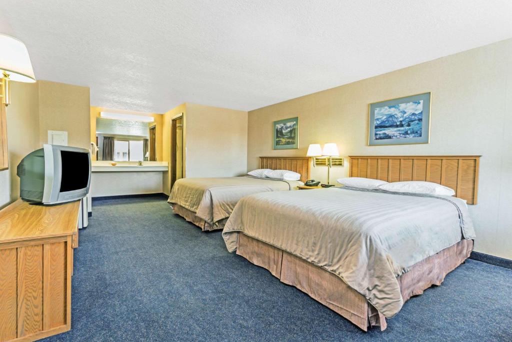 a hotel room with two beds and a flat screen tv at Travelodge by Wyndham Pioneer Villa in Halsey